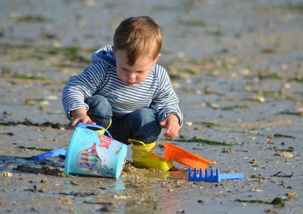 Enfant jouant seul à creuser et construire dans le sable sur la plage