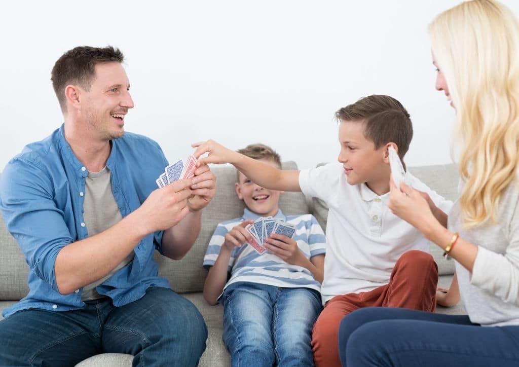 Parents et enfants s'amusent avec un jeu de cartes en famille