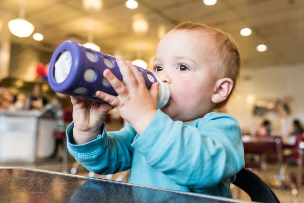 Bébé tenant un biberon protégé par un étuis en silicone