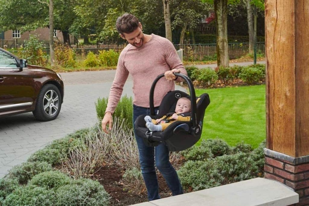 Un jeune papa portant le maxi cosi Citi de Bébé Confort