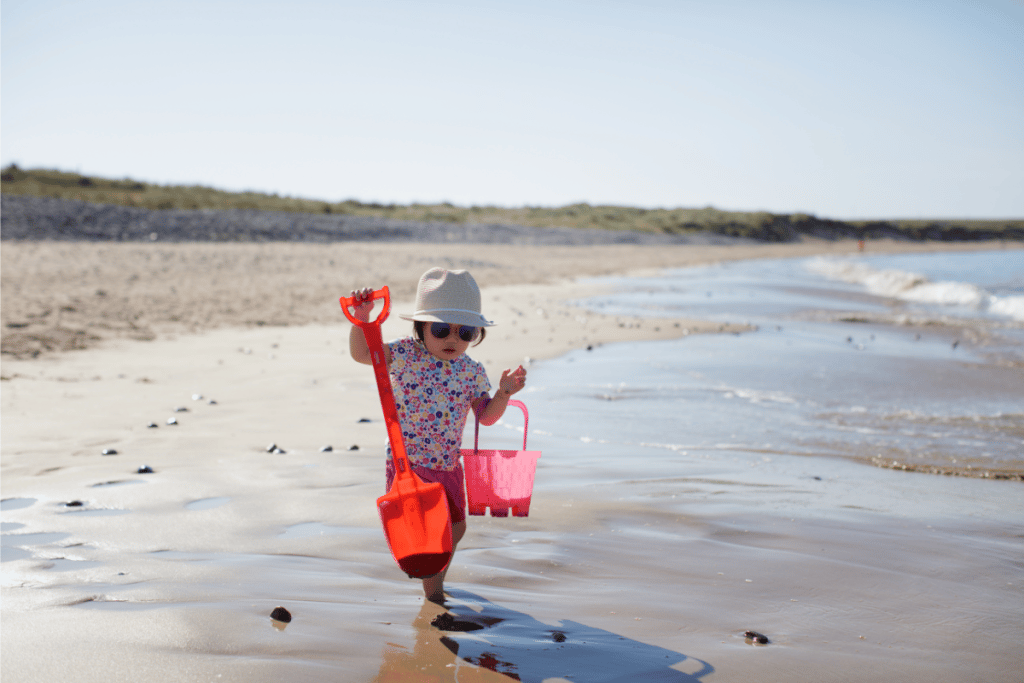 Tout-petit sur la plage portant des lunettes de soleil et un chapeau