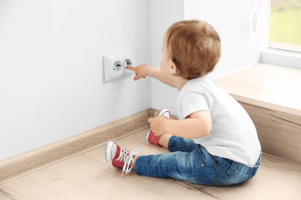 Jeune enfant mettant ses mains dans une prise électrique