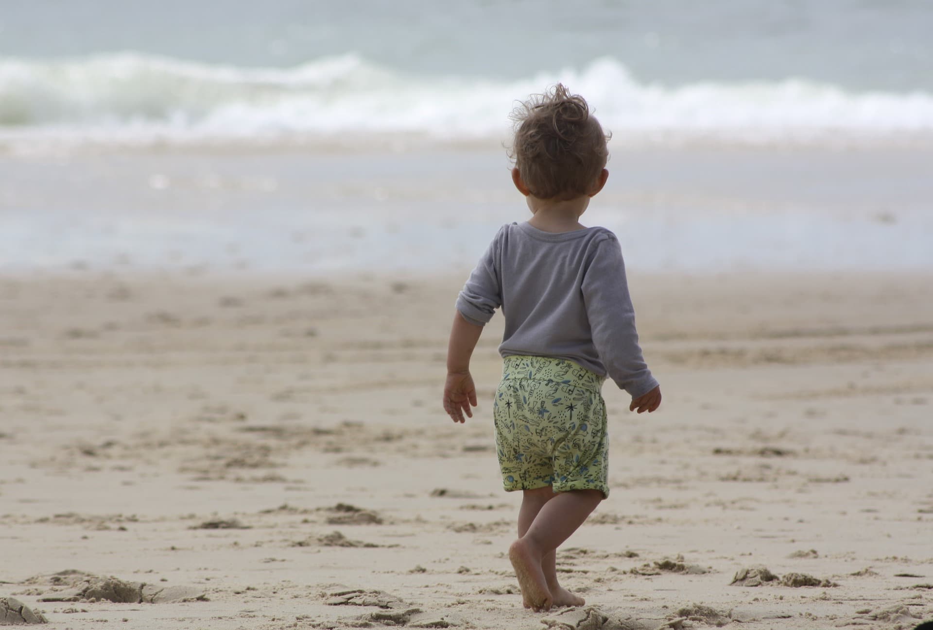 Bébé sur la plage faisant face à la mer