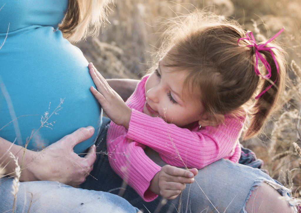 Petite fille touchant le ventre de sa mère enceinte